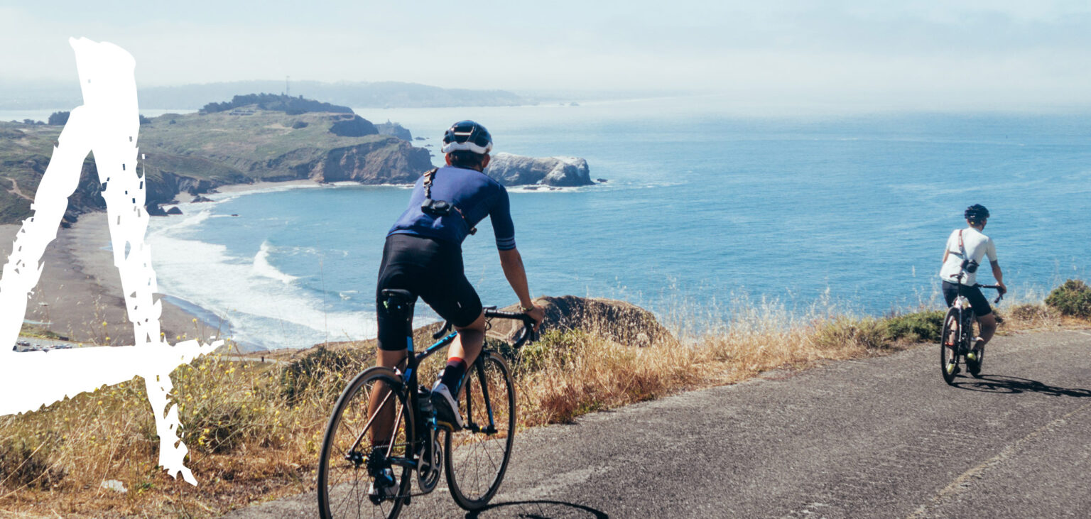 Two cyclists riding a coastal road above the Pacific